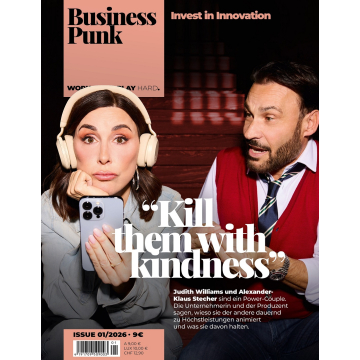 Zwei Personen sitzen nebeneinander, die linke trägt helle Kopfhörer und hält ein Smartphone, die rechte trägt ein rotes Oberteil mit weißem Hemd und Krawatte