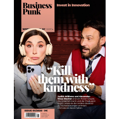 Zwei Personen sitzen nebeneinander, die linke trägt helle Kopfhörer und hält ein Smartphone, die rechte trägt ein rotes Oberteil mit weißem Hemd und Krawatte